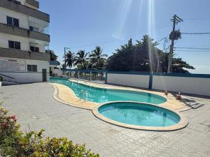 a swimming pool in a courtyard next to a building at Cobertura de Frente Para o Mar e Piscina Village das Ondas in Piúma