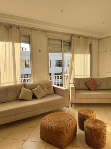 a living room with a couch and two tables and windows at Maison azur in Tunis