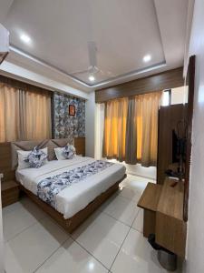 a bedroom with a large bed and a desk in it at Hotelsuncity inn in Vadodara