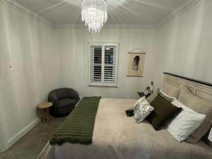 a bedroom with a large bed and a chandelier at Hollyberry House in Cooma