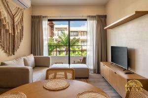 a living room with a couch and a tv at Xunik Tulum 205 1BR Condo in Tulum