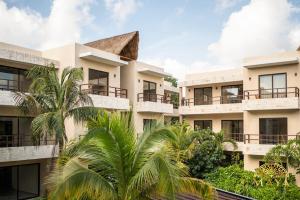a building with palm trees in front of it at Xunik Tulum 205 1BR Condo in Tulum