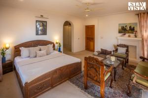 a bedroom with a large bed and a living room at StayVista at Hampton Grove - Bonfire, Jacuzzi in Srinagar