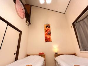 Una habitación con dos camas y un cuadro en la pared. en 梅小路公園近辺の民宿, en Kioto