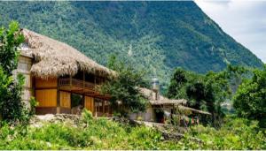 a house with a straw roof on top of a hill at Cha Ta Homestay & Trekking Tour Sa Pa in Sa Pa