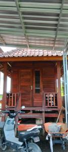ein Roller, der vor einem Holzhaus parkt in der Unterkunft Little bird lodge in Kuripan