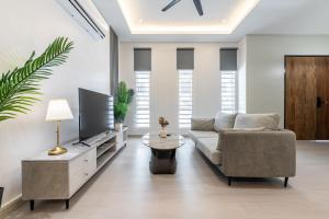 a living room with a couch and a tv at La Ferringhi Villa - 5 Bedroom Bungalows by ALV in Batu Ferringhi