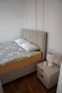 a bedroom with a bed and a nightstand with a lamp at Apartman Iskra in Bijeljina