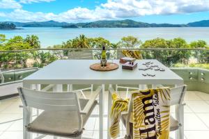 汉密尔顿岛Lagoon Beachfront Lodge 202 on Hamilton Island by HamoRent的阳台上摆放着桌子和椅子，可以欣赏到水景