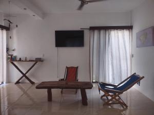 a living room with a table and a chair and a television at Casita viento in El Cuyo