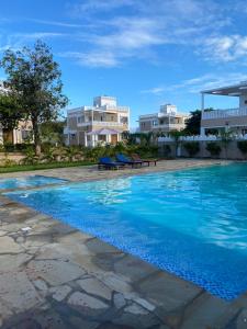 a swimming pool with blue water in front of buildings at Almond 7 in Gazi