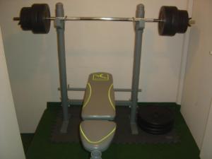 a gym with a bench and a barbell at Logis Hôtel Les 3B in Nouilhan