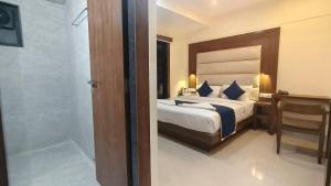 a bedroom with a bed and a bathroom with a shower at Hotel Ashraya International in Mumbai