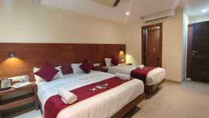 a hotel room with two beds with red and white pillows at Hotel Ashraya International in Mumbai +39 photos