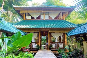 a house with a wooden walkway in front of it at Villa Boreh Beach Resort and Spa in Tejakula