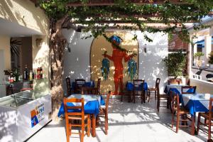 an outdoor dining area with tables, chairs and umbrellas at Narkissos Hotel in Kamari