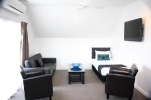 a living room with a couch and a bed and a tv at Camelot On Ulster in Hamilton