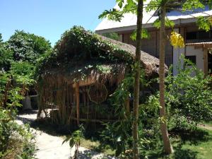 uma casa com telhado de palha no jardim em Bongo Bongo Divers em Dauin