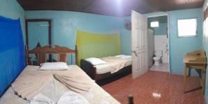 a bedroom with two beds and a bathroom with a sink at Casa El Buen Descanso in Moyogalpa