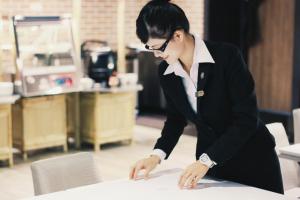 Une femme en costume assise à une table dans l'établissement Kindness Hotel-Jue Ming, à Kaohsiung