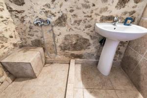 a bathroom with a sink and a stone wall at Tsikalaria Traditional Stone House in Tsikalariá