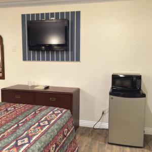 ein Hotelzimmer mit einem Bett und einem TV an der Wand in der Unterkunft Royal Inn in Lomita