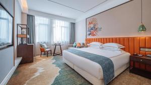 a hotel room with a large bed and a table at Wellay Hotel Ningbo Jiangbei Olympic Sports Center in Ningbo