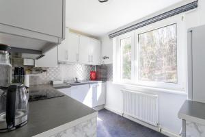 a kitchen with white cabinets and a large window at Natur View Apartment in Kaltenleutgeben