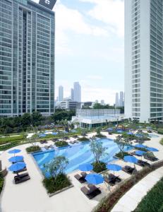 an aerial view of a resort pool with blue umbrellas at Fraser Place Setiabudi Jakarta in Jakarta