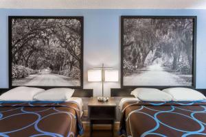 a hotel room with two beds and a cross on the wall at Super 8 by Wyndham Hardeeville - Savannah North in Hardeeville