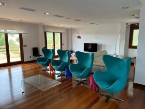 a living room with blue chairs and a table at Disfrutar de las rias baixas in Vilagarcia de Arousa