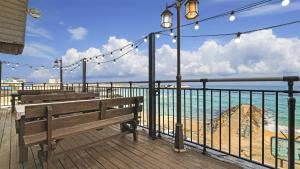 eine Holzterrasse mit Bänken und Strandblick in der Unterkunft Gangneung Haerang Pension in Gangneung