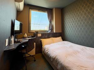 a bedroom with a bed and a desk with a computer at Hotel Areaone Naruto in Naruto