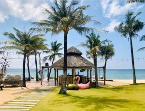 ein Pavillon am Strand mit Palmen in der Unterkunft Coral Hotel Phu Quoc in Phu Quoc