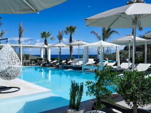 - une piscine avec des chaises longues et des parasols dans l'établissement Aurora Luxury Suites, à Imerovigli