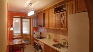 a kitchen with wooden cabinets and a white refrigerator at Svetlana's Apartments in Sumy