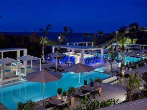 a pool with tables and umbrellas at night at Aurora Luxury Suites in Imerovigli