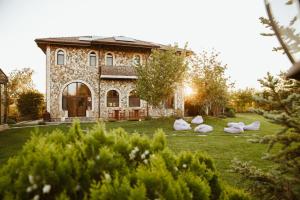 a stone house with white sculptures in front of it at Country SPA Village in Ciofliceni