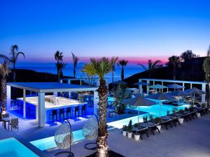 a resort with a pool and tables and umbrellas at Aurora Luxury Suites in Imerovigli