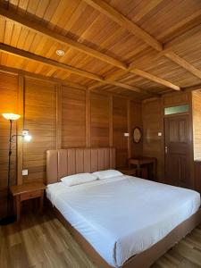 a bedroom with a large white bed with wooden walls at Awandari Resort & Convention in Kangkakawal +20 photos