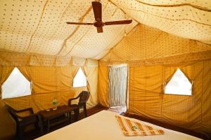 a tent with a ceiling fan and a table and chairs at Bubbles of luxury Dublagadi Beach in Sindhia
