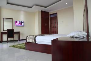 a bedroom with a bed and a desk with a phone at Namayiba Park Hotel Kampala in Kampala