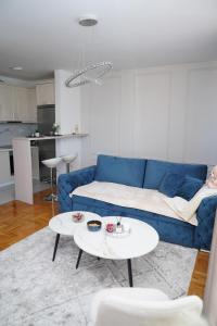 a living room with a blue couch and a table at Apartman Iskra in Bijeljina +10 photos