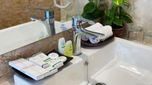 ein Waschbecken mit Wasserhahn und Toilettenartikeln darauf in der Unterkunft Lorin Syariah Solo Hotel in Solo