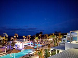 a resort with a pool and umbrellas at night at Aurora Santorini in Imerovigli