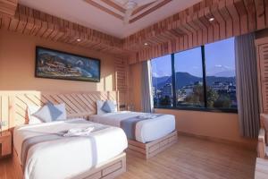 duas camas em um quarto com uma janela grande em Trekkers Inn Boutique Hotel Pokhara em Pokhara
