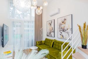 a living room with a green couch and a staircase at Palanga Suites in Palanga