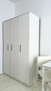 biała szafka w białym pokoju z krzesłem w obiekcie Beautiful Rooms - Wały Chrobrego w Szczecinie