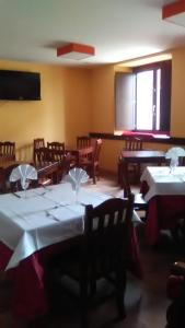 un comedor con mesas, sillas y una pantalla en El Albergue Covaleda, en Covaleda
