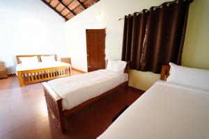 a bedroom with two beds and a window at Trogon resort in Kabini River
